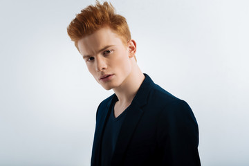 Determination. Attractive unsmiling red-haired young man wearing a jacket and staring and having a...