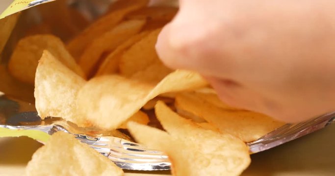 Hand taking potato chips from package