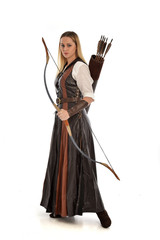Fototapeta premium full length portrait of girl wearing brown fantasy costume, holding a bow and arrow. standing pose on white studio background. 