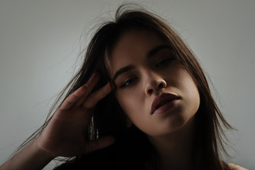 Meditative. Beautiful thoughtful dark-haired young woman staring and touching her temple and...