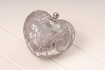 metal evening handbag, clutch has heart shape, handbag is on white background, sparkly grey handbag