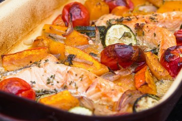Roasted salmon with various vegetables in brown baking tray