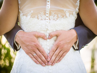 Groom creating heart shape with his hands on the back of the bride.Couple in love. Close up of...