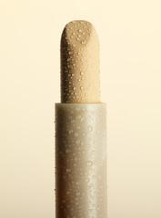 still life of natural lipstick sprinkled with droplets