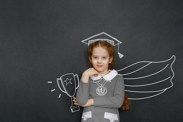 Smart curly girl near green chalkboard in classroom.