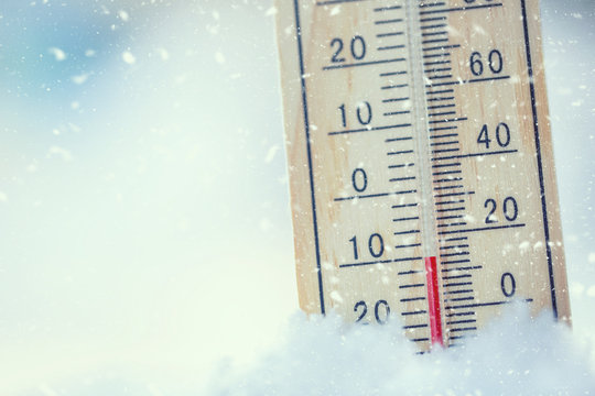Thermometer on snow shows low temperatures under zero. Low temperatures in degrees Celsius and fahrenheit. Cold winter weather ten under zero.