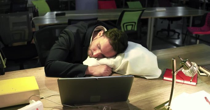 Sales manager is sleeping on table using white pillow afte hard busy day. Late work overtime concept.