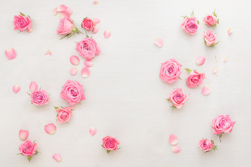 Fototapeta na wymiar Roses background. Various pink roses buds and petals scattered on white background, overhead view, copy space