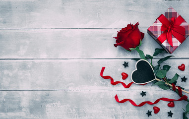 Valentine background with red rose flower and small present box on rustic wood. Happy lovers day gift mockup, copy space