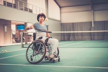 Disabled mature woman in wheelchair on a tennis court