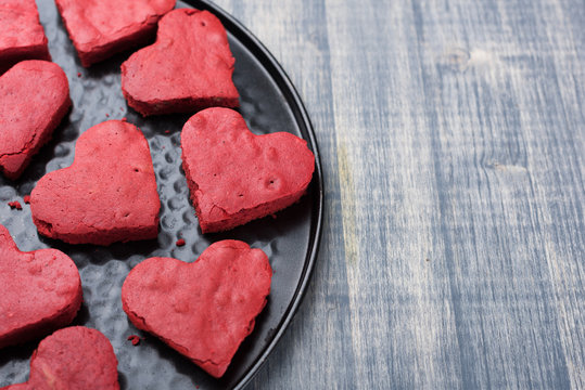 Red velvet heart cookies on plate. Baking tray with sweet biscuit cakes. Valentine days food