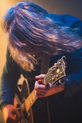 Close up of rock guitarist with long hair playing during concert