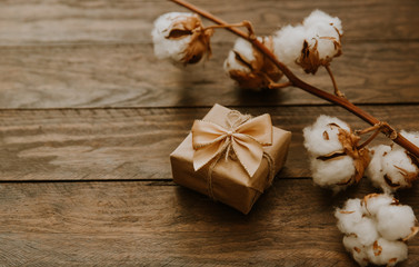 Vintage gift box with cotton flowers over wooden background