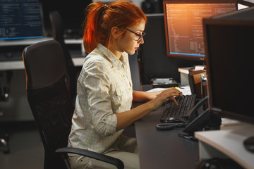 Late at night, a dedicated red hair female programmer works diligently, driven by determination and...