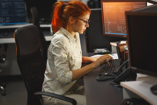 Late at night, a dedicated red hair female programmer works diligently, driven by determination and fueled by coffee, as she strives to meet project deadlines and embrace innovation.