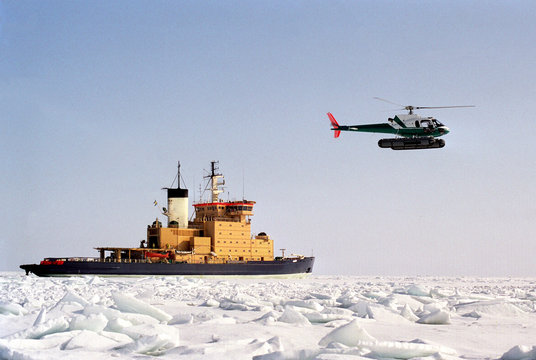 Helicopter flying over yellow icebreaker ship