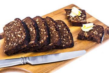 Rye bread with grains and butter on wooden kitchen board