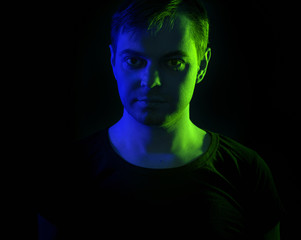 Portrait of a man with colored light and dark background.