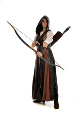 full length portrait of girl wearing brown  fantasy costume, holding a bow and arrow, on white studio background. 