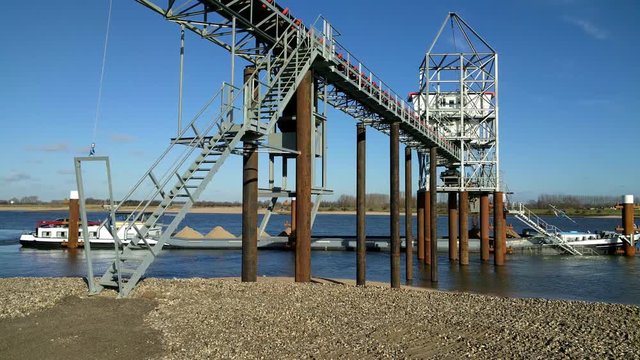Loading an inland ship with sand using a conveyor.