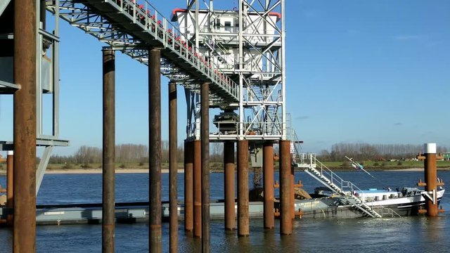 Loading a barge with sand using a conveyor - medium shot.