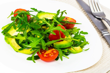 Vitamin vegetarian salad from arugula and avocado on white plate