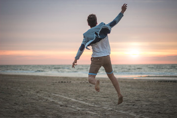 boy jumping into the sunset at the beach