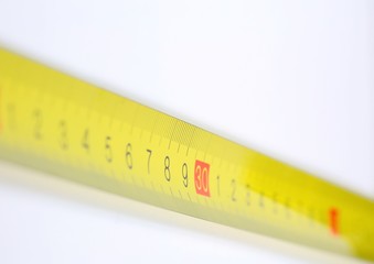 Yellow metallic decimal tape measure on white background. Selective focus.