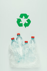 top view of recycle sign and plastic bottles in plastic bag isolated on grey