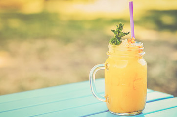 A fresh juice on a wooden table outdoor.
