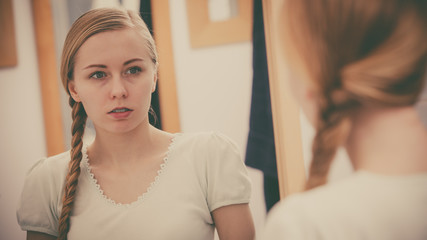 Fototapeta premium Woman looking at her reflection in mirror