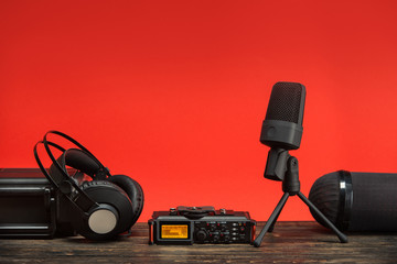 equipment for field audio recording on red background.  usb microphone, recorder, headphones,...