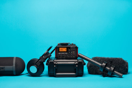 equipment for field audio recording on blue background. Windshield, shotgun microphone,  recorder, portable case and headphones