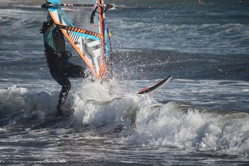 Through the waves. Girl windsurfing at the Atlantic ocean
