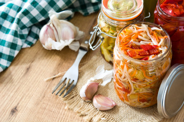 Fermented preserved vegetables in jar on wooden table. Copyspace