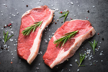 Raw beef striploin steak. Top view on black table.