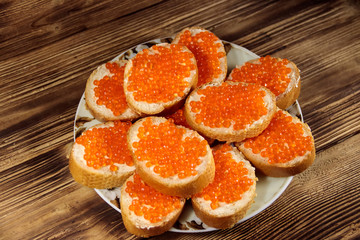 Sandwiches with butter and red caviar on wooden table