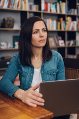 Thoughtful woman sitting working in a library