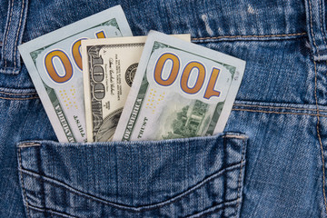 One hundred American dollars bills in the pocket of blue jeans
