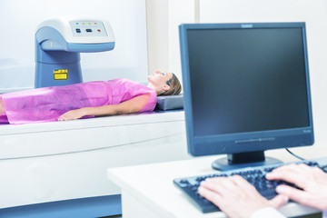 Woman in 40s undergoing medical x-ray with elderly doctor looking at monitor