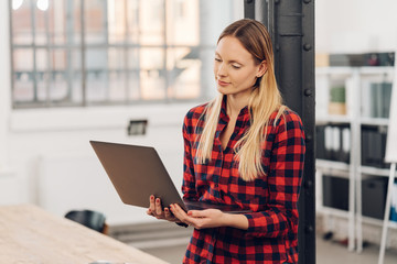 Attractive blond woman using a handheld laptop