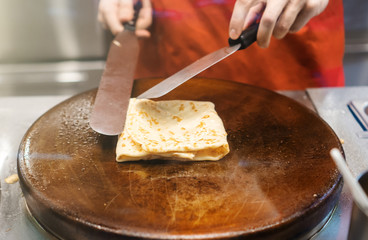 Preparation of pancake. Cook works in the kitchen.