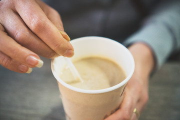Woman's hands holding disposable coffee cup.