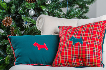 pillow with image of a dog lying on the chair. Background Christmas tree