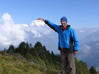 Happy hiker on Poon Hill, Dhaulagiri range on the backround - one of the most visited Himalayan view points in Nepal, view to snow capped Himalaya