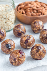 Healthy homemade energy balls with cranberries, nuts, dates and rolled oats on parchment, vertical