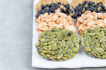 Korean traditional sweet snacks with peanuts, pumpkin seeds, black soybeans and chinese buckwheat on white plate, horizontal, copy space
