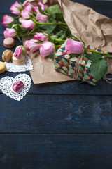 A bouquet of pink roses, a box with a gift. Sweet pasta macaroons of different colors, on Valentine's Day.