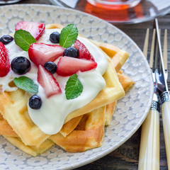 Homemade belgian waffles with yogurt, strawberry and blueberry, breakfast time, square