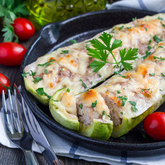 Fototapeta na wymiar Zucchini boats stuffed with ground meet and topped with cheese on cast iron pan, square format